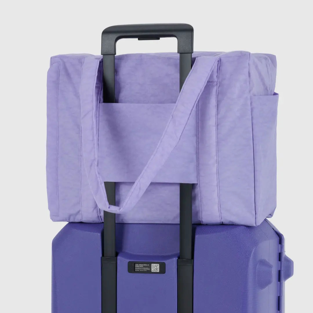 Purple suitcase with a matching tote bag on a light gray background