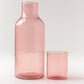 Pink glass carafe and tumbler on a light gray background
