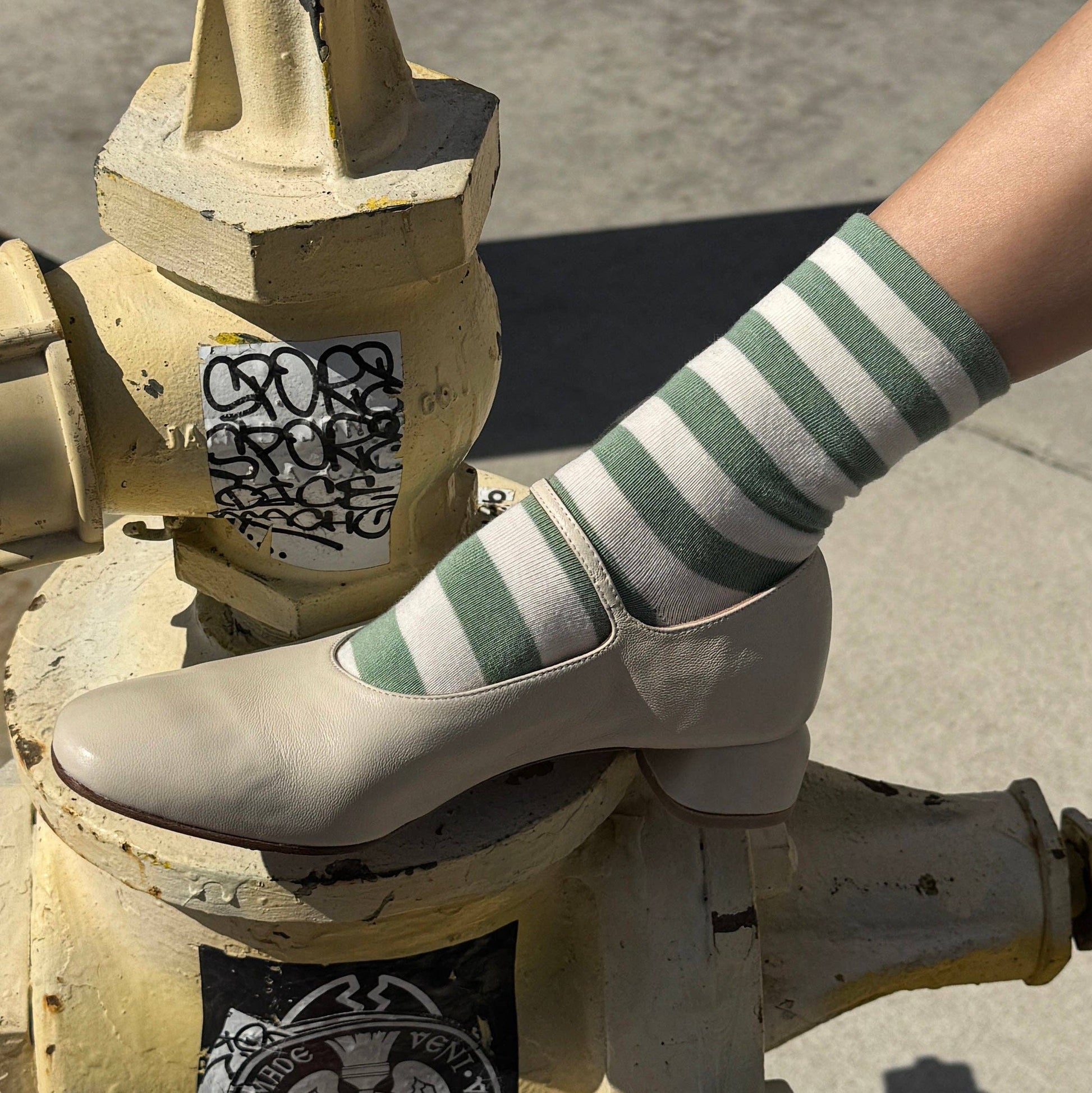 Person wearing striped socks standing on a fire hydrant