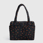 Black handbag with red cherry pattern on a light gray background