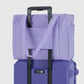 Purple suitcase with a matching tote bag on a light gray background
